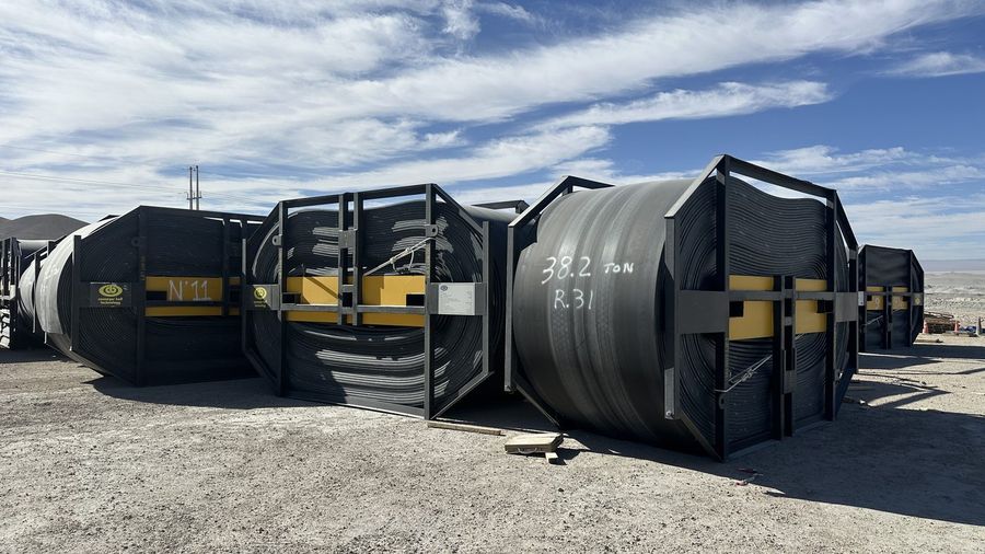 Carretes con correa transportadora de acero apilados en patio, remate Codelco